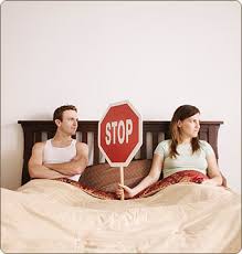 Мужчина и женщина в постели, женщина держит знак «Стоп»